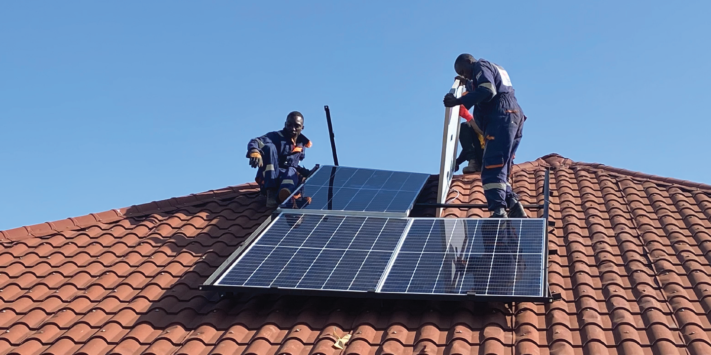 Engineers installing solar panels on tiled rooftop